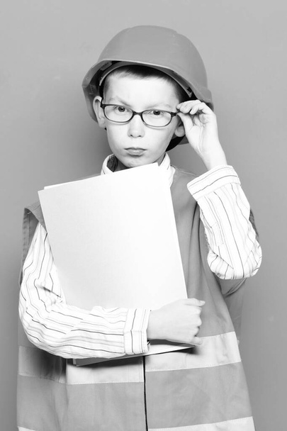 young cute builder boy on red studio background - 写真・画像