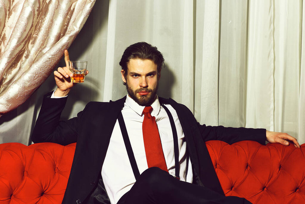 bearded man, businessman holding glass of whiskey in red tie - Zdjęcie, obraz