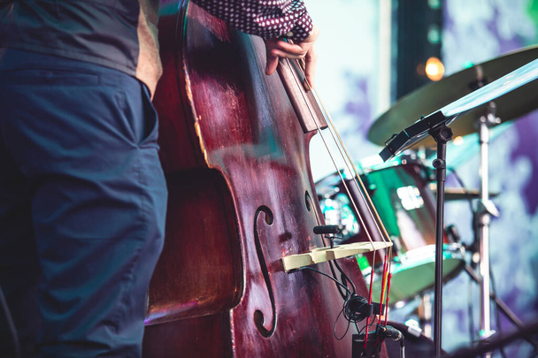 Concert view of a contrabass violoncello player with vocalist and musical band during jazz orchestra band performing music, violoncellist cello jazz player on stag - Foto, Imagen