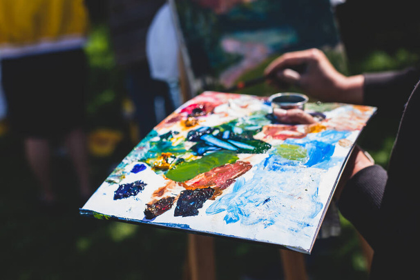 Process of plein air painting, group class of adult talented students in the park with paints easels, and canvases during lesson of watercolour painting outdoors  - Fotoğraf, Görsel