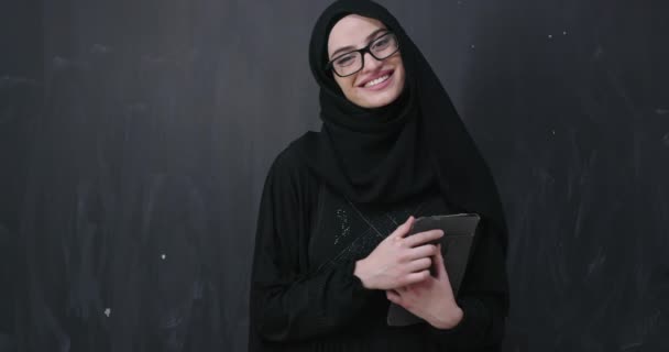 portrait of beautiful muslim woman in fashionable dress with hijab making traditional prayer to God keeps hands in praying gesture isolated on black chalkboard background representing modern islam fashion and ramadan kareem concept - Imágenes, Vídeo
