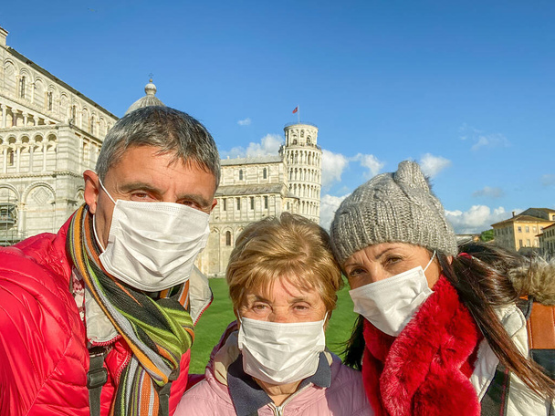 Yüz maskesi takan üç kişilik bir aile ünlü simgeyi ziyaret ediyor.. - Fotoğraf, Görsel