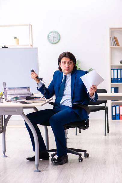 Молодой бизнесмен, сидящий и работающий в офисе - Фото, изображение