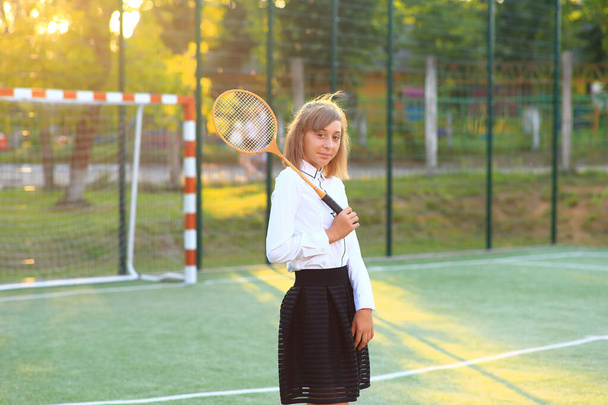 Ein Mädchen in Schuluniform mit einem Schläger in der Hand auf dem Fußballplatz. - Foto, Bild