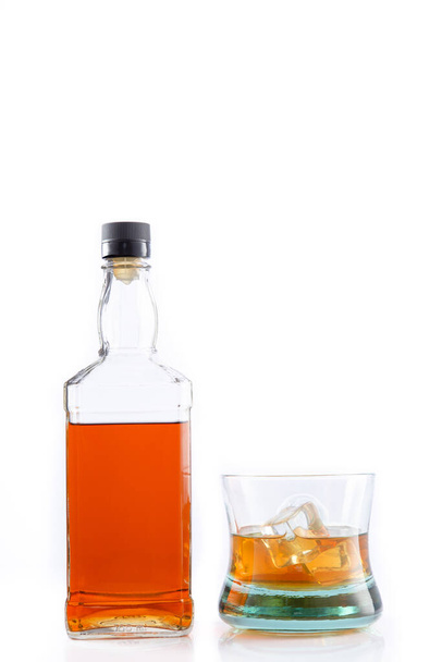 Egy üveg whisky és egy üveg whisky jéggel, fehér alapon elkülönítve, fénymásoló térrel.. - Fotó, kép
