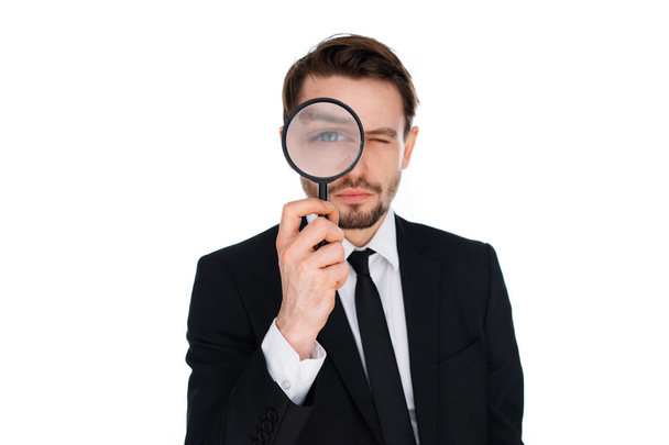 Businessman looking through a magnifying glass - Фото, изображение