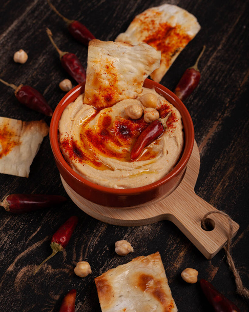 Fresh hummus with paprika on a black table - 写真・画像