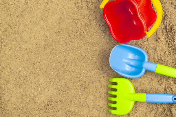 Otwarta piaskownica. Piaskowe zabawki dla dzieci: łopata, grabie i wiadro. Koncepcja letnia. - Zdjęcie, obraz