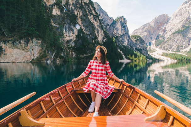 woman sitting in big brown boat at lago di braies lake in Italy. summer vacation - Fotoğraf, Görsel