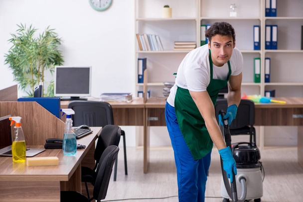 Fiatal jóképű vállalkozó takarítja az irodát - Fotó, kép