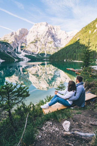 пара, сидящая на скамейке и смотрящая на озеро в горах - Фото, изображение
