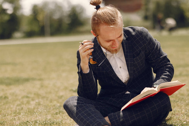 Businessman with book sitting in a summer city - Zdjęcie, obraz