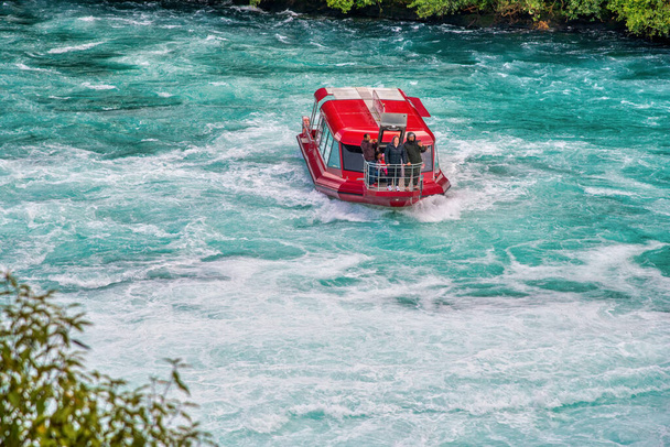 Czerwona łódź pod prąd wodny w Huka Falls, Nowa Zelandia. - Zdjęcie, obraz