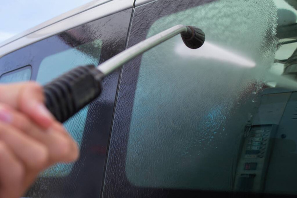 cleaning car with water hose at a gas station and leaving it shiny and glossy - Фото, изображение