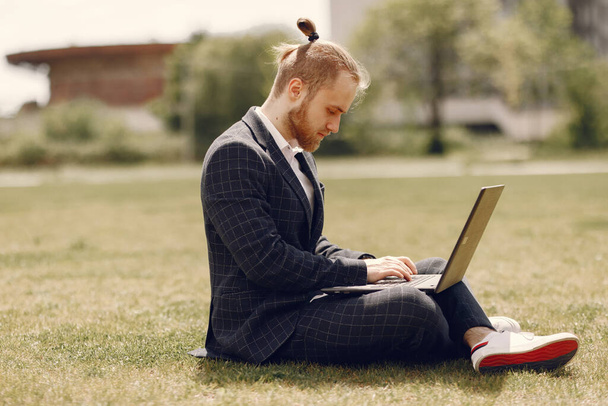 Businessman with laptop in a summer city - Foto, afbeelding