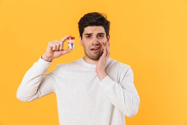 Photo of handsome unhappy man with allergy posing with medicine isolated over yellow background - Фото, изображение