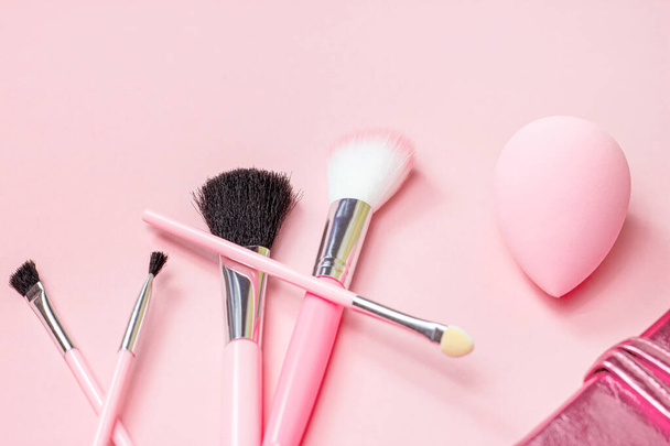 Bovenaanzicht van helder roze decoratieve cosmetica tools en accessoires voor professionele make-up en gezicht op lichte achtergrond met kopieerruimte. - Foto, afbeelding