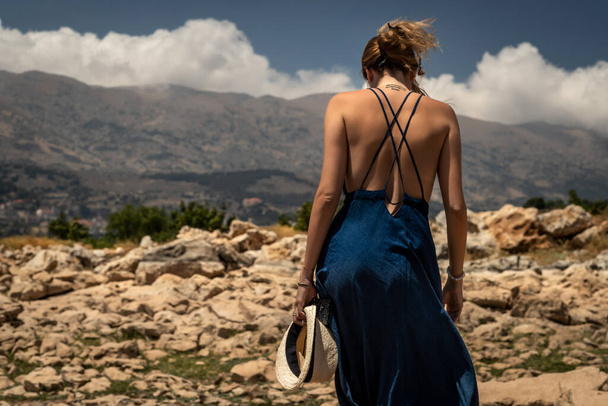 Back Side of a Beautiful Young Woman Standing on the Top of the Mountains. Enjoying Amazing Mountainous View. Happy Peaceful Summer Vacation. - Foto, imagen