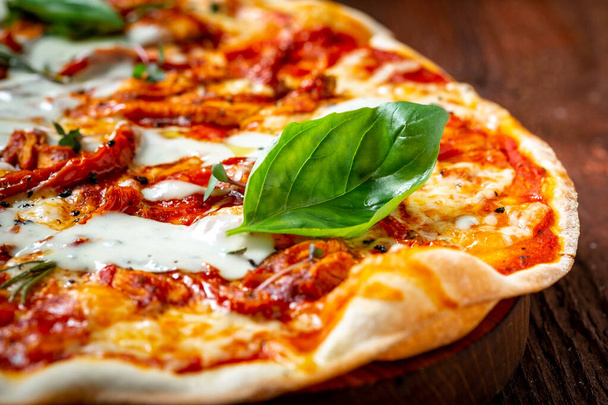 Pizza lunga Margarita con pomodori secchi e basilico su tavola di legno, da vicino. Cucina italiana in stile rustico - Foto, immagini