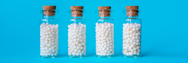 Imagen de banner de glóbulos homeopáticos en botellas de vidrio sobre fondo azul pastel. - Foto, imagen