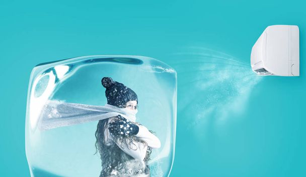 Woman frozen in an ice cube under the air jet of an air conditioner on cyan background - Photo, Image