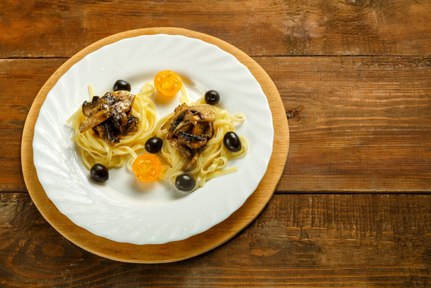 White plate with spaghetti nests stuffed with mushrooms. - Foto, Bild