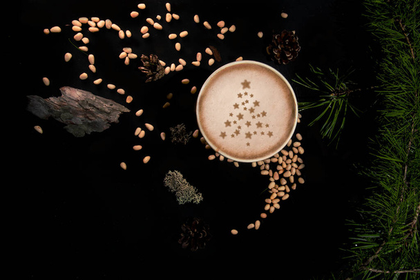 Flat lay with paper cup of coffee on black background with pine tree and cedar seeds - Valokuva, kuva