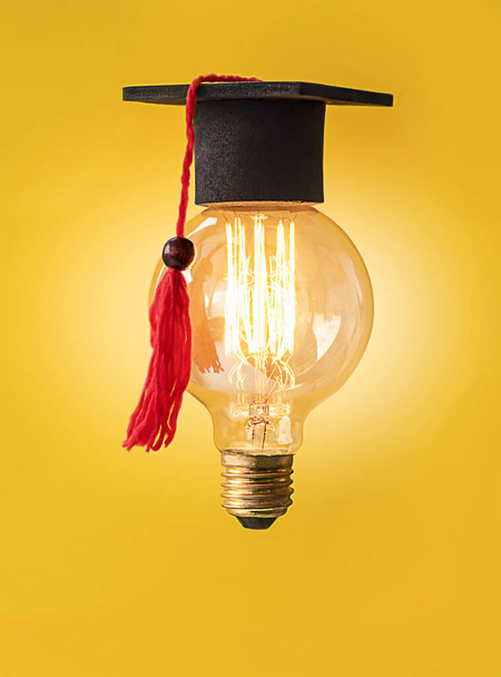 una bombilla encendida en una gorra de graduado - Foto, Imagen