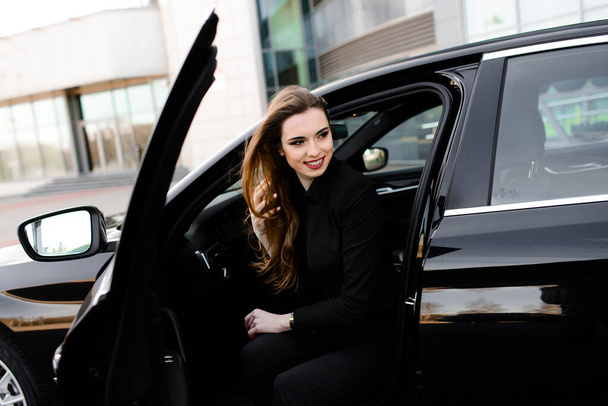 Young businesswoman in black wear with expensive car - Фото, изображение