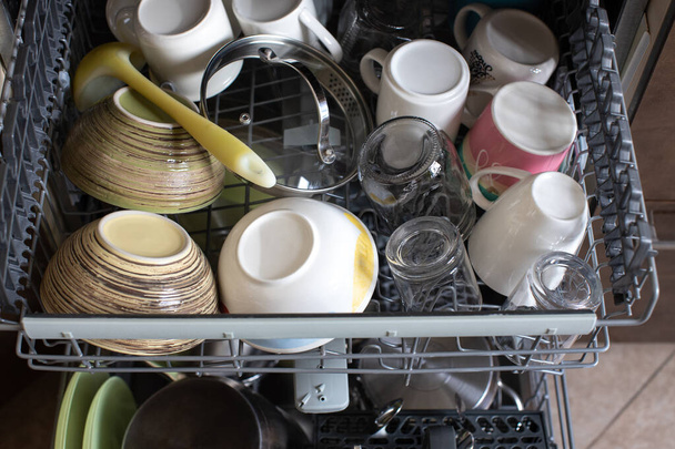 Clean dishes in dishwasher. Freshly washed dishes, plates, cups, jars, mugs, cutlery, pots. Concept of hygiene, household, home care, water saving, technologies and helpers in everyday life. - Zdjęcie, obraz