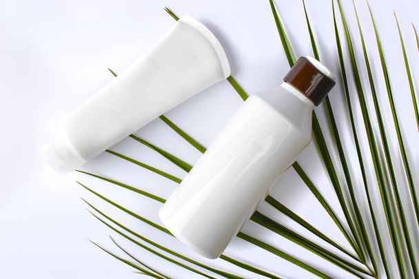 Pojemniki na butelki kosmetyczne z zielonymi liśćmi ziołowymi, Blank label for branding mock-up, Natural beauty product concept. - Zdjęcie, obraz