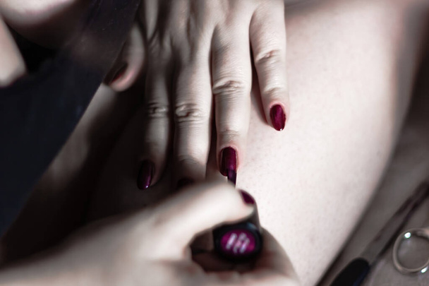 Caucásico hembra hace auto esmalte de uñas viendo tutorial en el teléfono celular a través de Internet - Foto, Imagen