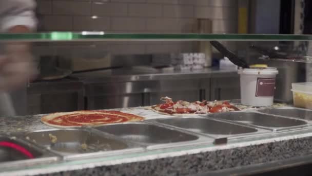 Hands of chef in fast food restaurant put ingredients on pizza view through showcase. Pizza concept. Food production and delivery. Delicious, ingredient. Shot in 4k resolution. Italian food - Footage, Video