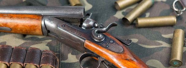 Hunting rifle with ammunition against a camouflage background - Photo, Image