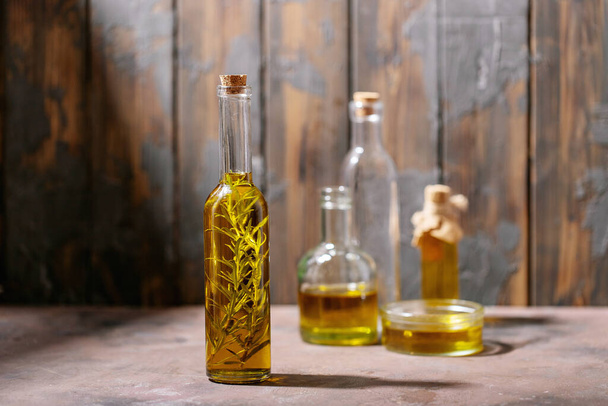 Olive oil with rosemary in glass bottles over dark wooden background. Top view, flat lay. Copy space - Fotó, kép
