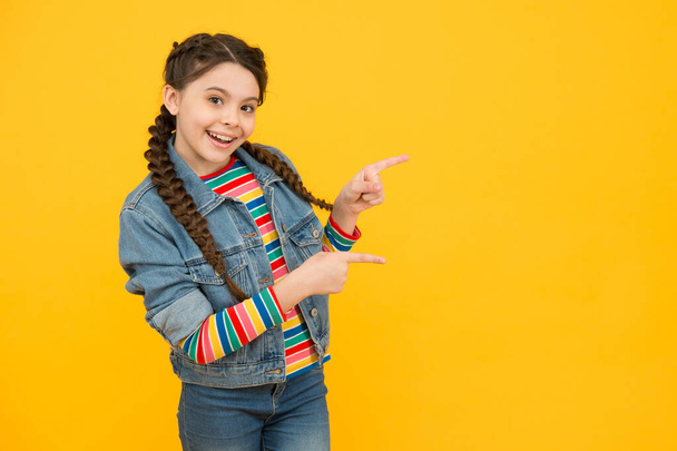 Excited little girl with braids wear denim clothes, promoting goods concept - Photo, Image