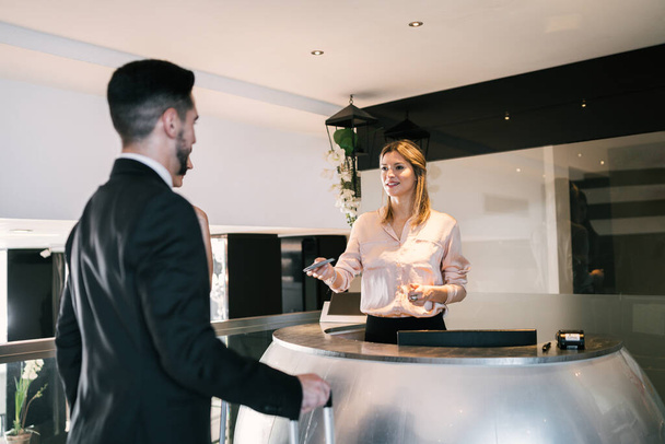 Portrait of two young business people check-in at hotel reception front desk. Business travel concept. - Foto, Bild