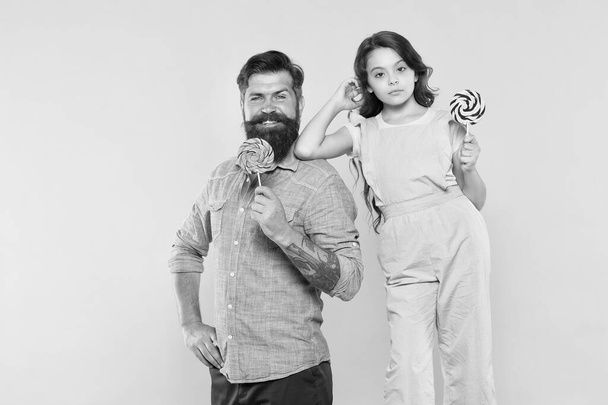 Eat dessert first. Happy family hold candy dessert on stick. Father and daughter yellow background. Bearded man and child. Sweet dessert. Candy shop. Sugar confectionery. Dessert time - Foto, Bild