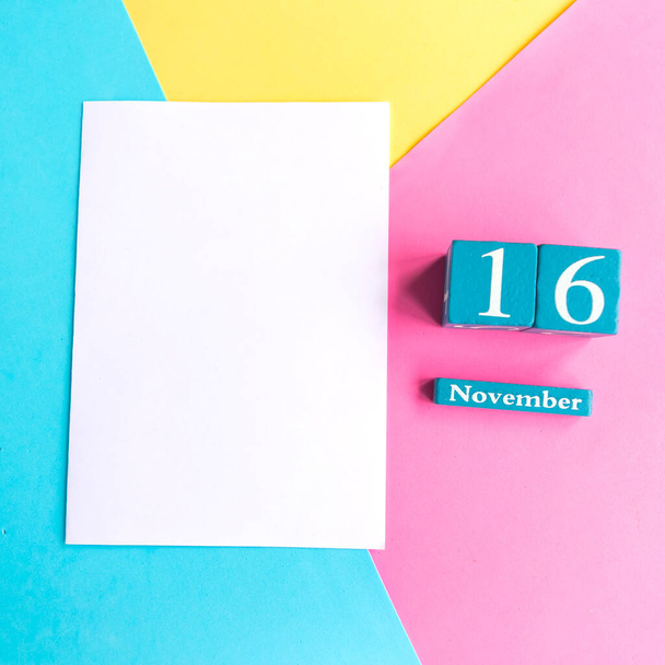 16 de Novembro. Calendário cubo azul com mês e data em fundo geométrico de cor
. - Foto, Imagem
