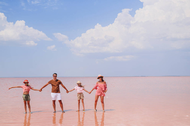 Οικογενειακή βόλτα σε μια ροζ αλμυρή λίμνη σε μια ηλιόλουστη καλοκαιρινή μέρα. - Φωτογραφία, εικόνα
