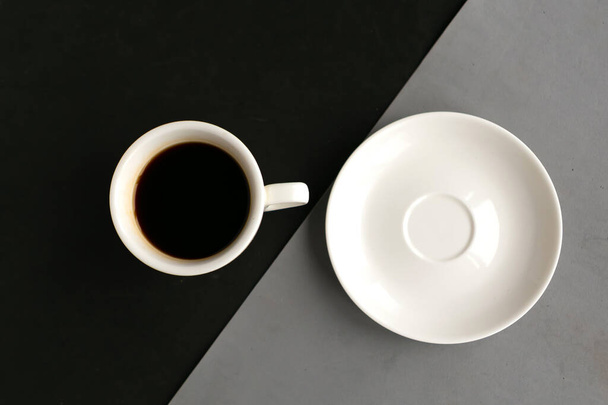 Пустая тарелка и кофейная чашка на геометрическом сером и черном фоне, вид сверху. Минимальная концепция - Фото, изображение