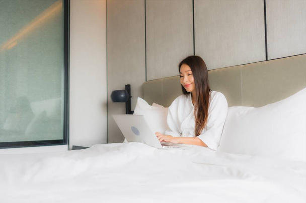 Muotokuva kaunis nuori aasialainen nainen käyttää kannettavaa tietokonetta tai tietokonetta makuuhuoneessa sisustus - Valokuva, kuva