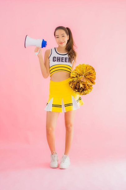 Portret mooie jonge aziatische vrouw cheerleader met megafoon op roze geïsoleerde achtergrond - Foto, afbeelding