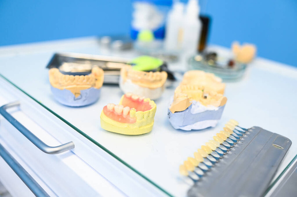 Dişçilerin stomatoloji kliniğindeki farklı diş aletleri, aletler ve aletler beyaz arka planda. Çenenin silikon kalıbı - Fotoğraf, Görsel