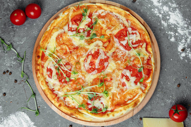 Pizza Margherita op zwarte stenen achtergrond, bovenaanzicht. Pizza Margarita met Tomaten, Basilicum en Mozzarella Kaas close up. - Foto, afbeelding
