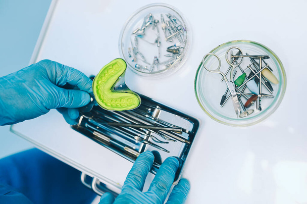 Erilaiset ammatilliset hammaslääkärin laitteet, välineet ja työkalut hammaslääkärin stomatologian toimisto klinikalla valkoisella taustalla. Silikoni valettu leuan - Valokuva, kuva