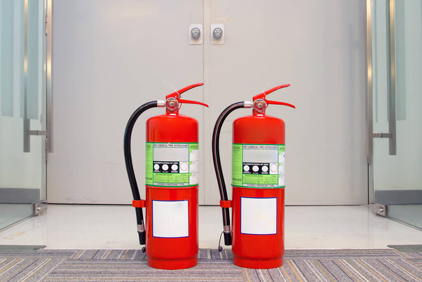 Sulje punainen palosammutin säiliö hätäuloskäynnin ovella rakennuksen turvallisuusjärjestelyjen pelastus- ja paloharjoituspalveluissa. - Valokuva, kuva
