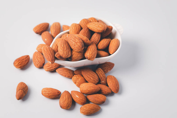 Almonds in a white ceramic cup on a white background - Photo, Image