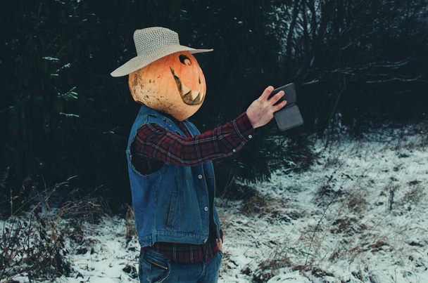 Espantapájaros de Halloween toma una selfie en su teléfono en el bosque de invierno - Foto, Imagen