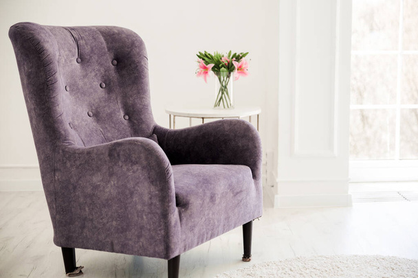 Purple corduroy armchair stands opposite the window. Horizontal photo - Foto, imagen